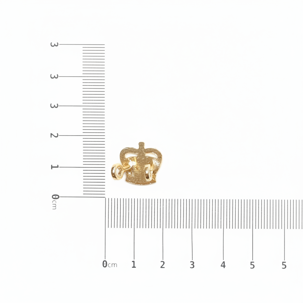 Gold crown badge with ruler for scale on white background
